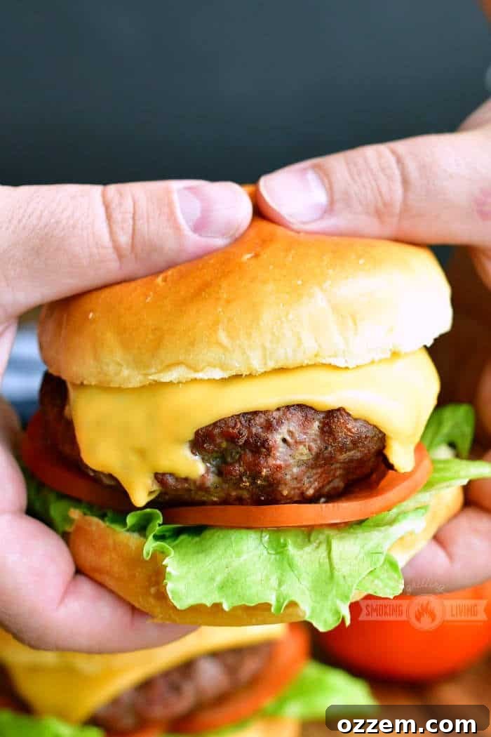 A hand holding a delectable cheeseburger with lettuce and tomato, showcasing its juicy interior and perfect grilling marks.