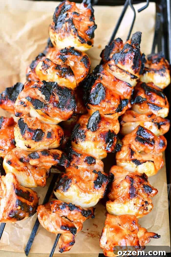 Perfectly cooked teriyaki chicken kebabs on skewers, resting on parchment paper on a tray, ready to serve.