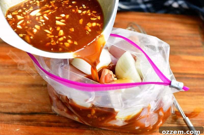 Teriyaki marinade being poured into a zip-lock bag containing cut chicken and onion pieces.