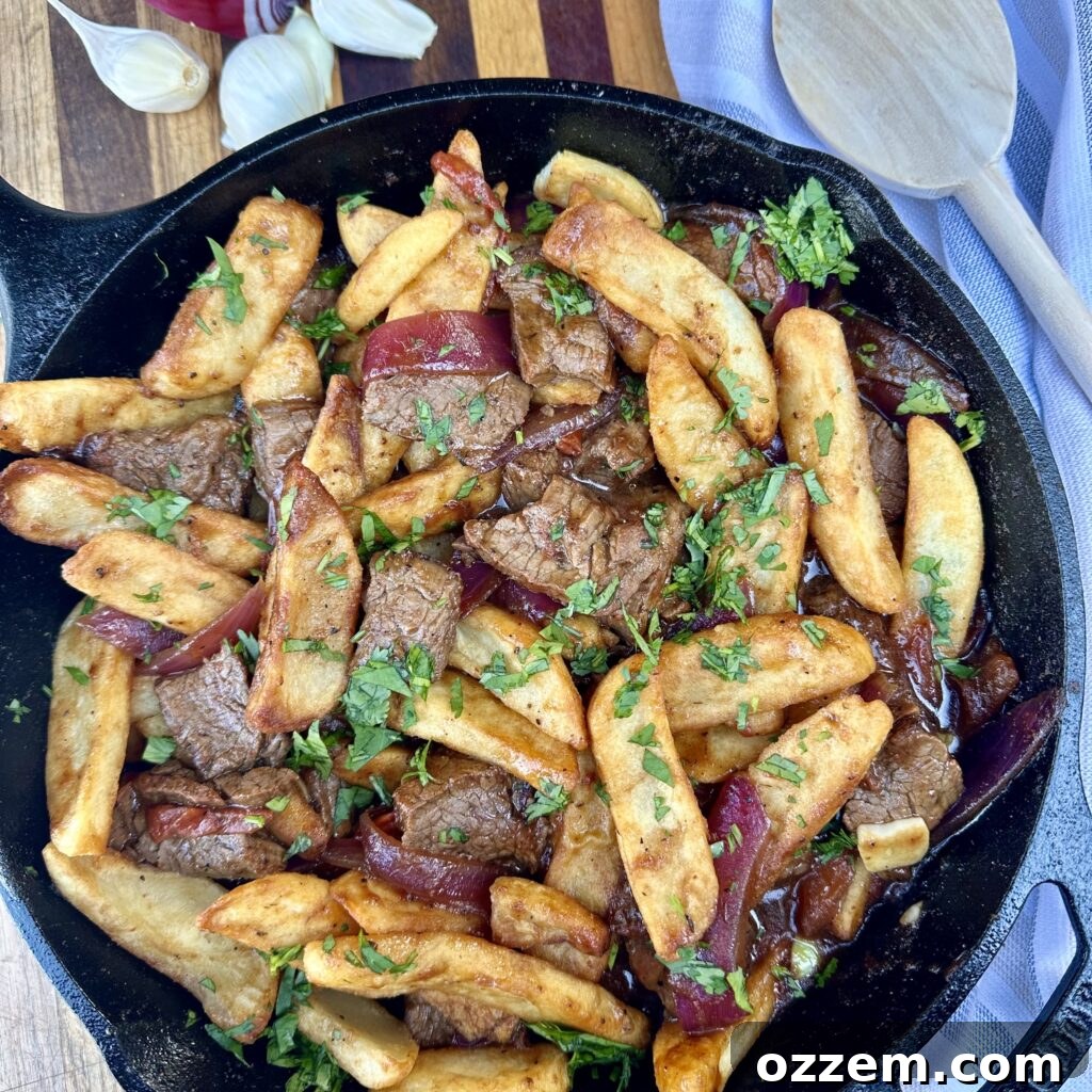 A vibrant and savory plate of Lomo Saltado, featuring tender beef, stir-fried vegetables, and golden French fries.