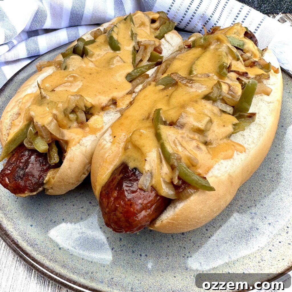 Gourmet Beer Cheese Hotdogs smothered in a rich, cheesy beer sauce, topped with vibrant sautéed bell peppers and onions, beautifully plated and ready to enjoy.