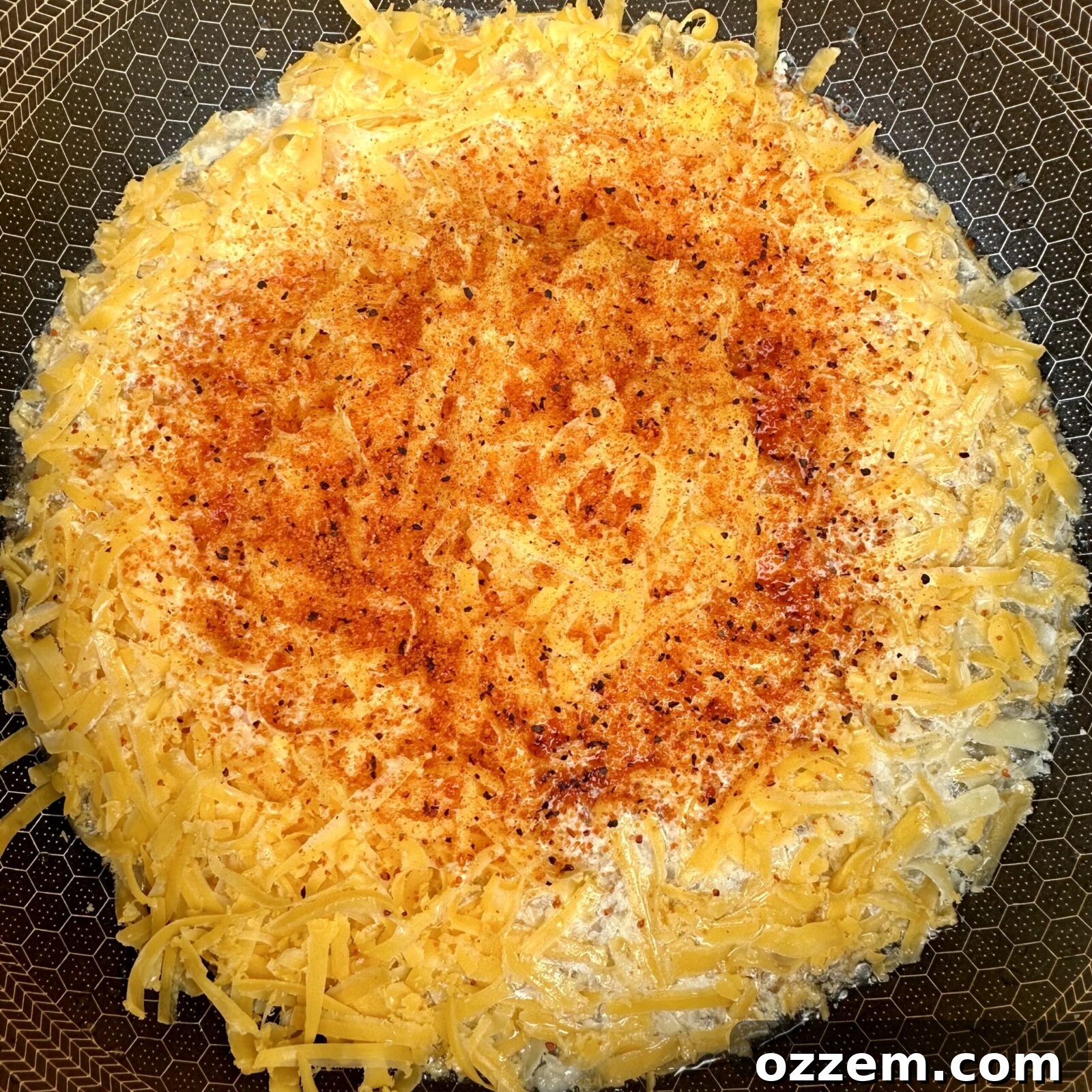 Creamy, golden beer cheese sauce in a saucepan, ready to be poured over hotdogs, highlighting its smooth texture.