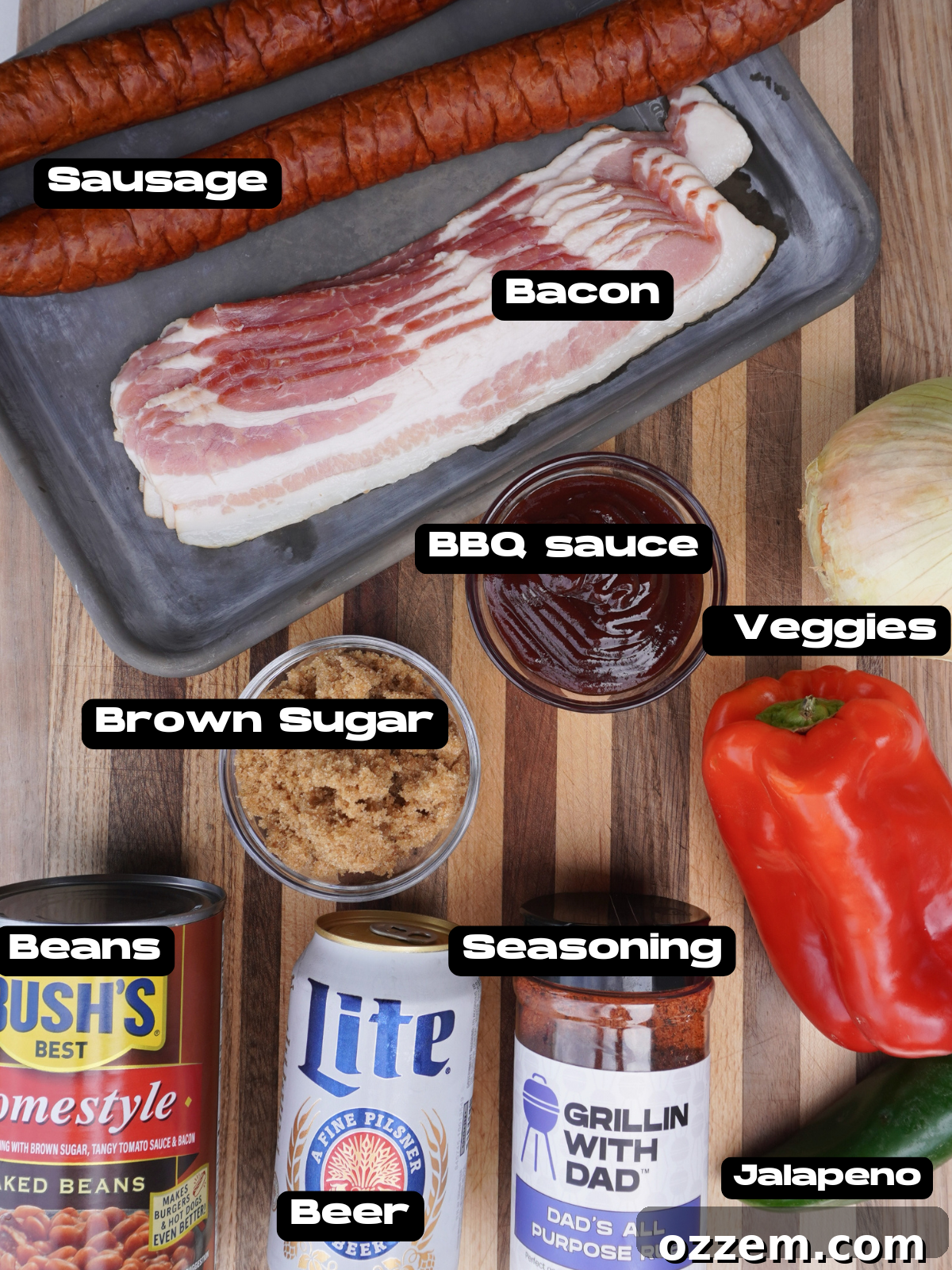 Assortment of fresh ingredients for smoked pit beans, including bacon, sausage, bell peppers, onions, beans, beer, and various sauces.