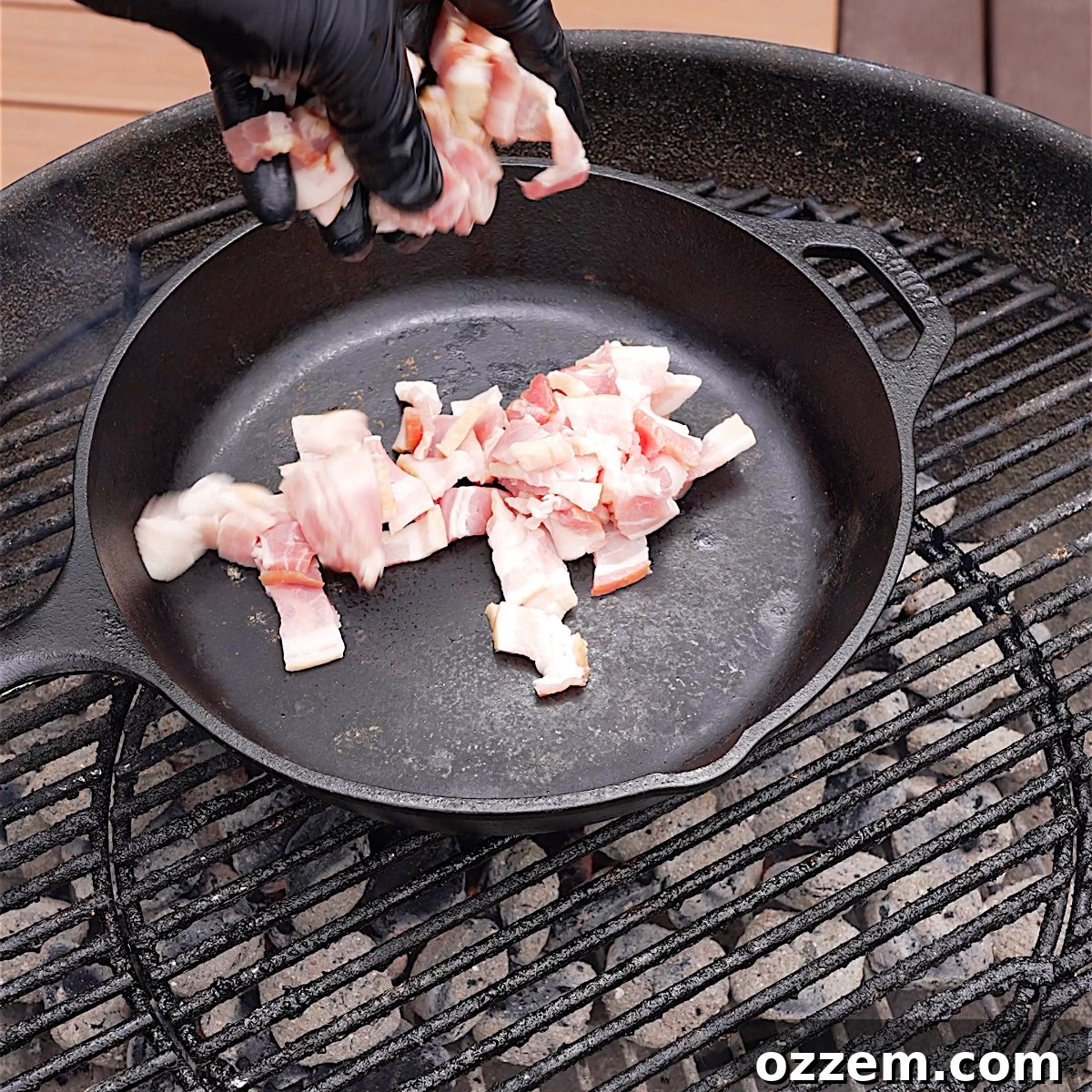 Raw thick-cut bacon diced and placed in a cold cast iron skillet, ready for grilling.