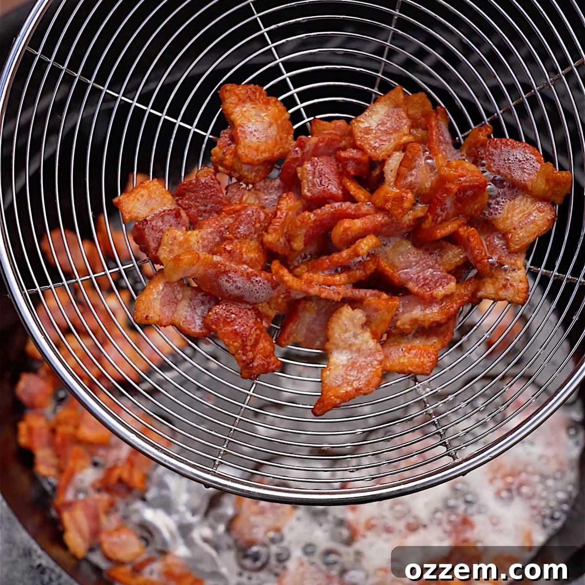 Crispy, golden-brown bacon sizzling in a cast iron skillet on a hot grill, with rendered grease at the bottom.