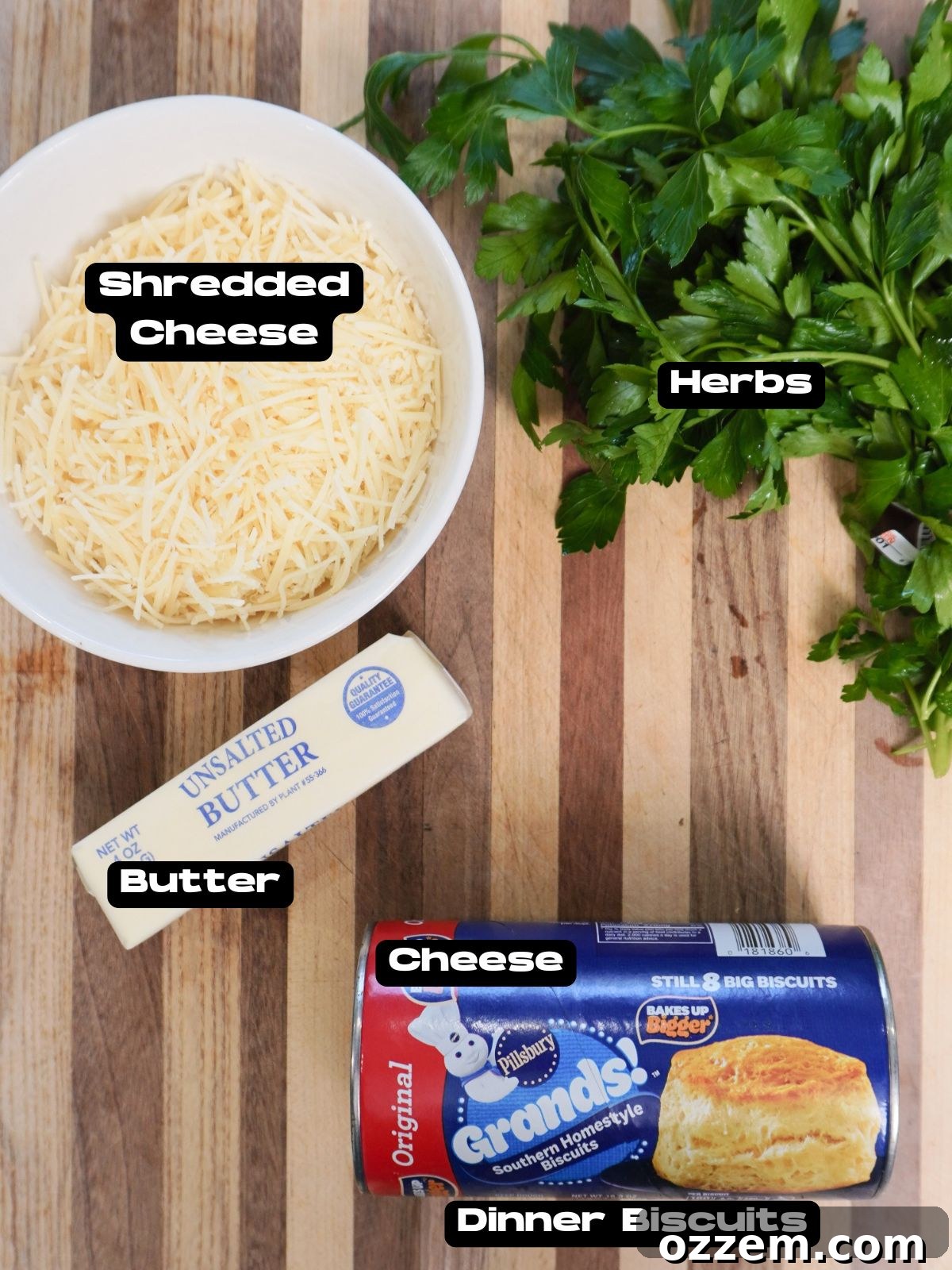 Savory Cheese Muffins 3 A flat lay of the simple ingredients required for cheesy dinner muffins, including refrigerated biscuits, butter, shredded cheese, and fresh parsley.