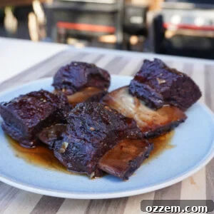 Cooked short ribs on a plate with sauce, glistening and ready to serve.