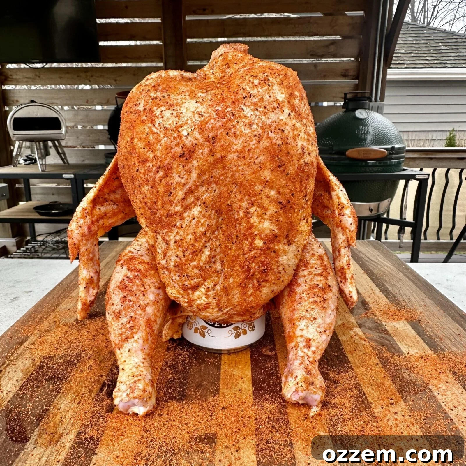 Whole chicken generously seasoned on a beer can, ready for smoking