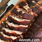 cut rack of baby back ribs on the wooden cutting board with a knife next to it