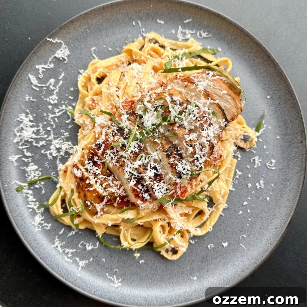 Marry Me Pasta with grilled chicken dressed with thin strips of basil on a grey plate, ready to be served.