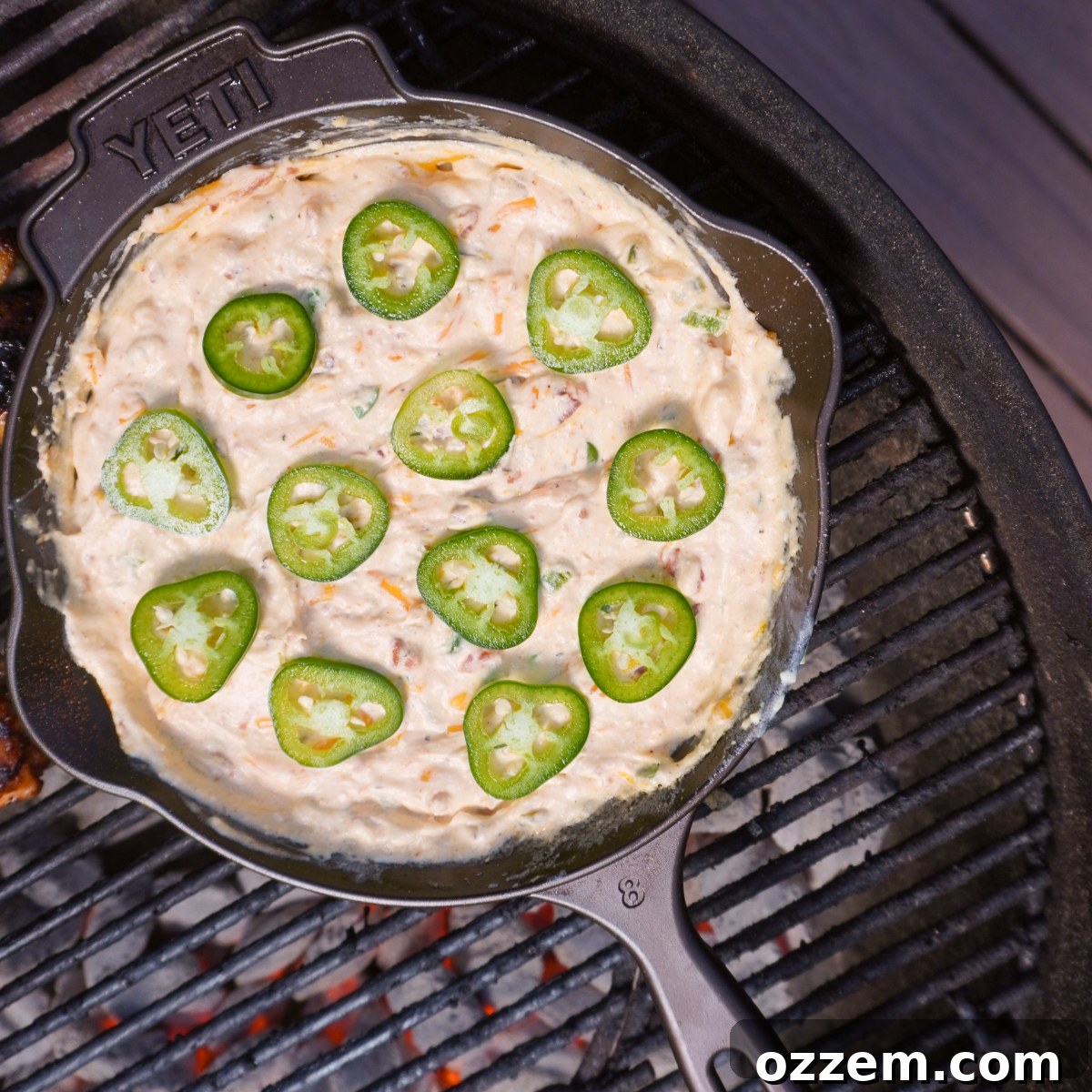 Raw jalapeno popper dip in a cast iron skillet on the grill