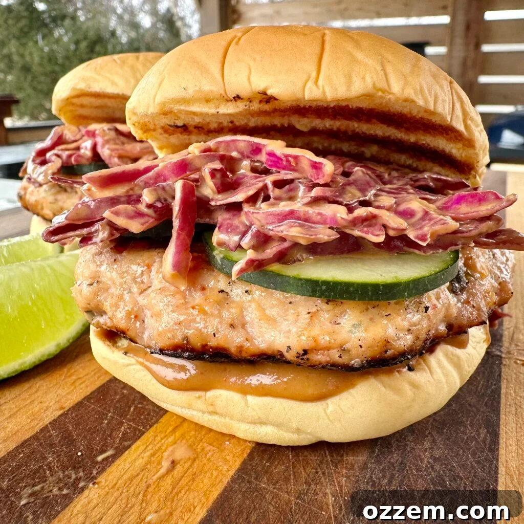Delicious Thai Inspired Chicken Burgers, topped with peanut slaw, on burger buns.