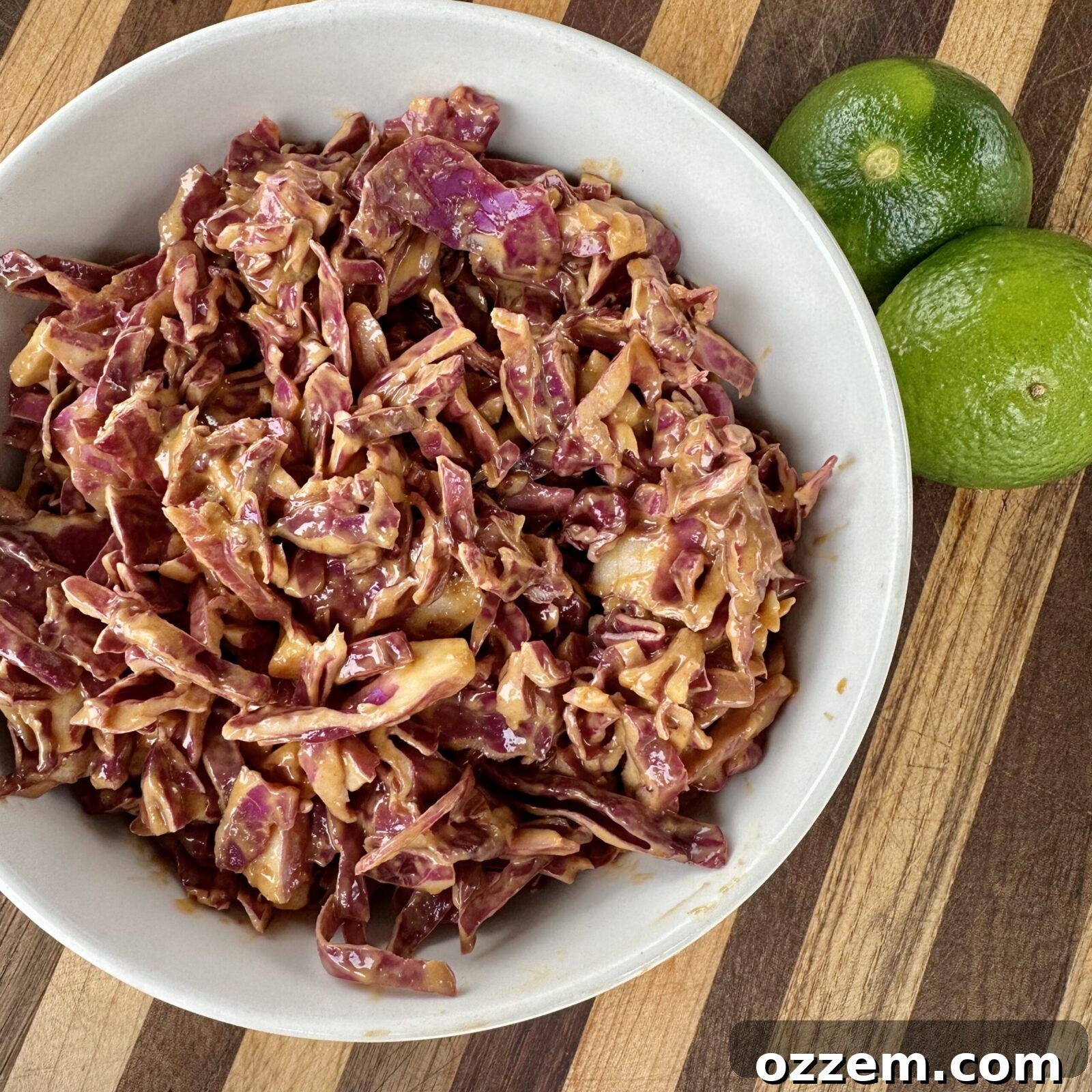 Vibrant red cabbage slaw generously coated in creamy peanut butter sauce, ready to top a delicious burger.