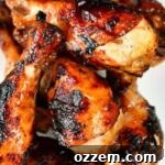 Grilled chicken legs marinaded and cooked stacked on a plate.