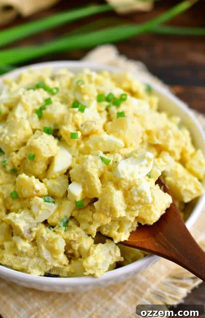using a wooden spoon to scoop out some potato salad from the white bowl