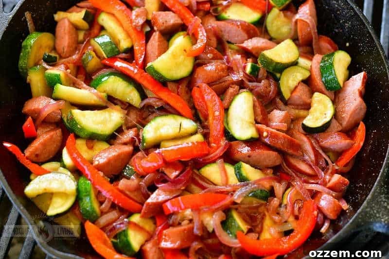 A vibrant close-up of colorful sausage, tender zucchini, red bell peppers, and sweet onion sizzling and caramelizing in a robust cast iron skillet on the grill, capturing the essence of a perfect outdoor meal.