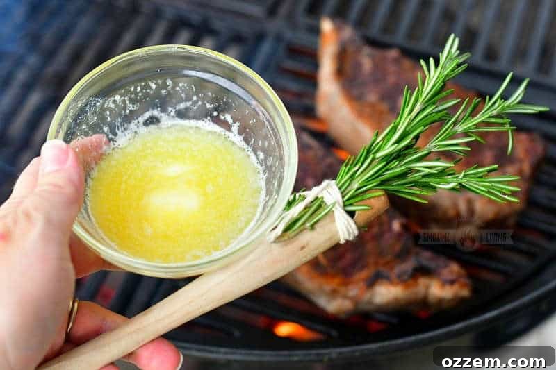 holding a small clear dish of melted butter and rosemary brush with steaks on the grill on the background