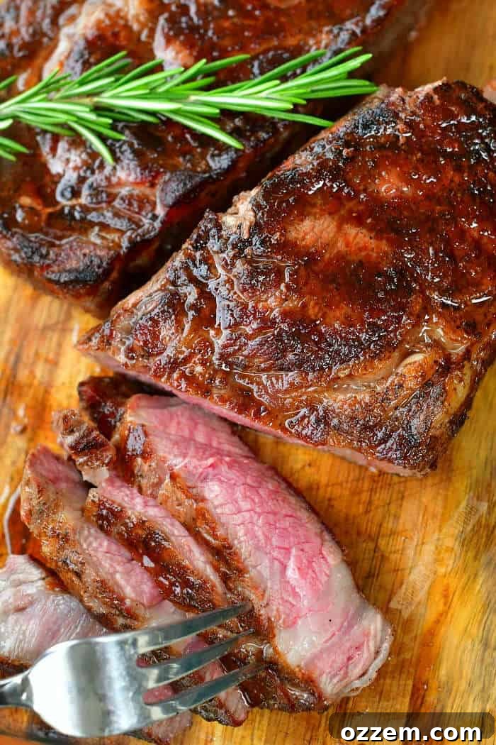 top view of sliced steak on the cutting board and a rosemary sprig on top