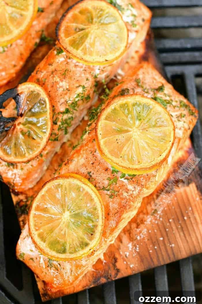 Smoky Cedar Plank Salmon with Zesty Lemon Herbs 2 top view of cooked salmon pieces with lemon slices on top on the plank on the grill