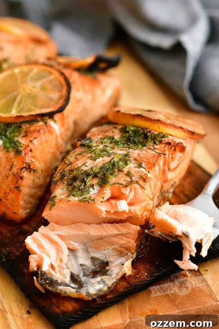 Smoky Cedar Plank Salmon with Zesty Lemon Herbs 6 cooked salmon with herbs on top and some salmon flaked off on a fork
