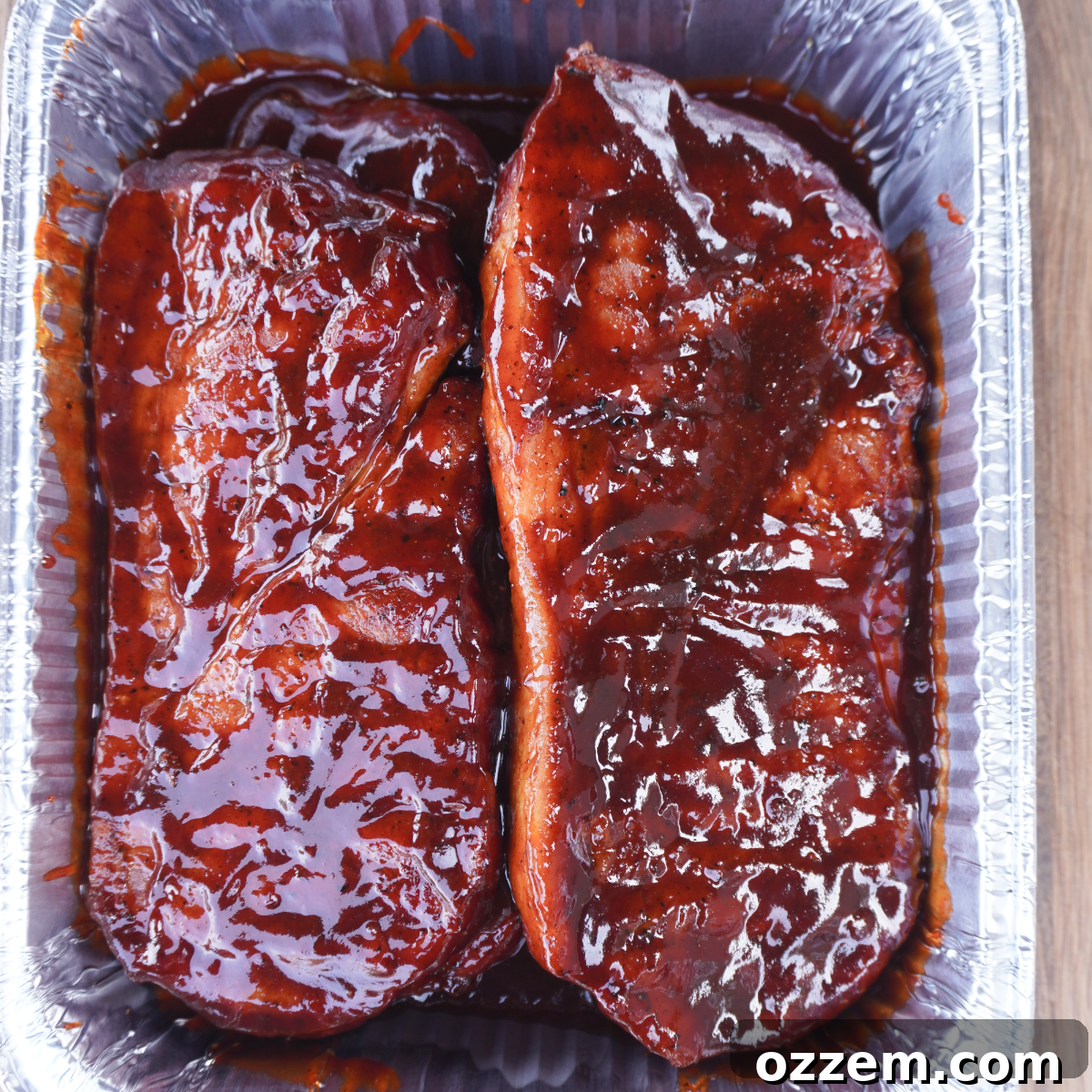 Pork steaks cooking on a grill over indirect heat, soaking up smoky flavors.