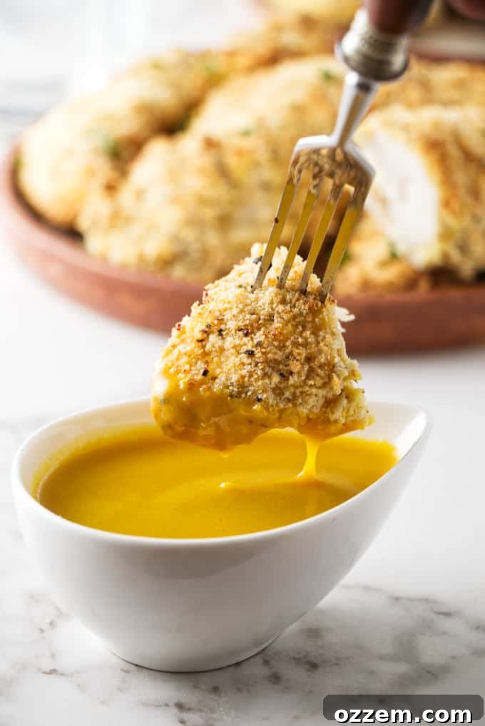 Crispy Parmesan Air Fryer Chicken Tenders 7 A close-up shot of a bite of air fryer chicken tender being dipped into a honey mustard sauce, showcasing its crispy texture.