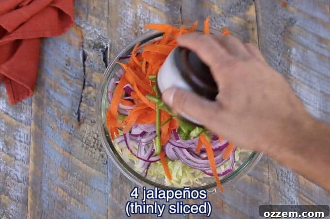 chopped vegetable ingredients for jalapeño lime cilantro slaw in a glass bowl on wood table