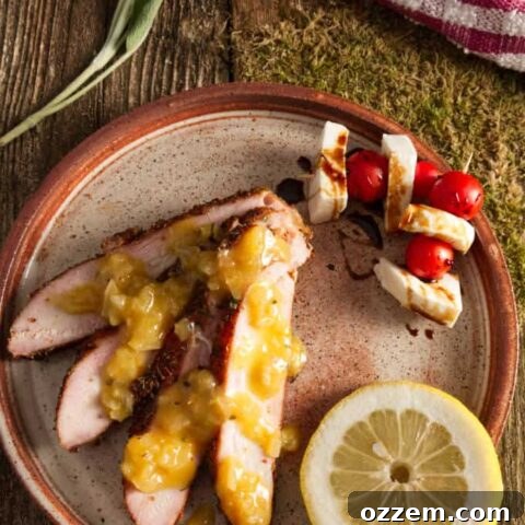 Perfectly smoked slices of wild turkey breast on a plate with caprese skewers and balsamic glaze drizzle. Orange butter sauce drizzled over the sliced turkey.
