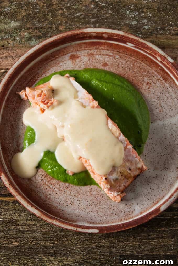 Zesty Citrus Beurre Blanc 4 Close-up shot of a grilled salmon fillet with a generous drizzle of creamy orange lemon butter sauce on top, highlighting the sauce's smooth texture.