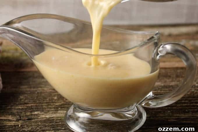 Zesty Citrus Beurre Blanc 8 A stream of smooth, creamy orange lemon butter sauce being poured from a saucepan into an elegant gravy boat, ready for serving.