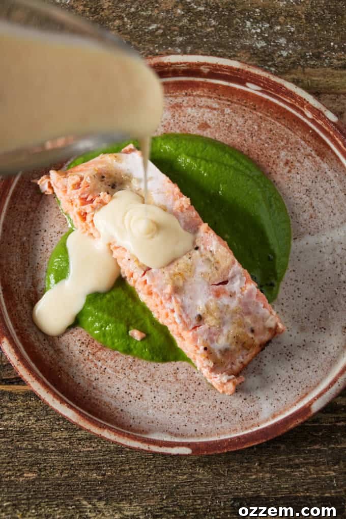 Zesty Citrus Beurre Blanc 9 Orange lemon butter sauce poured from a gravy boat onto a perfectly grilled salmon fillet, creating a delicious and visually appealing dish.