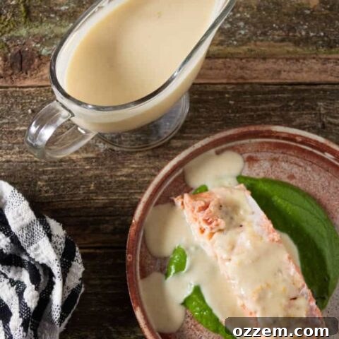 Orange Lemon Butter Sauce (Beurre Blanc) drizzled generously over a grilled salmon fillet, with a elegant gravy boat filled with the creamy sauce on the side.
