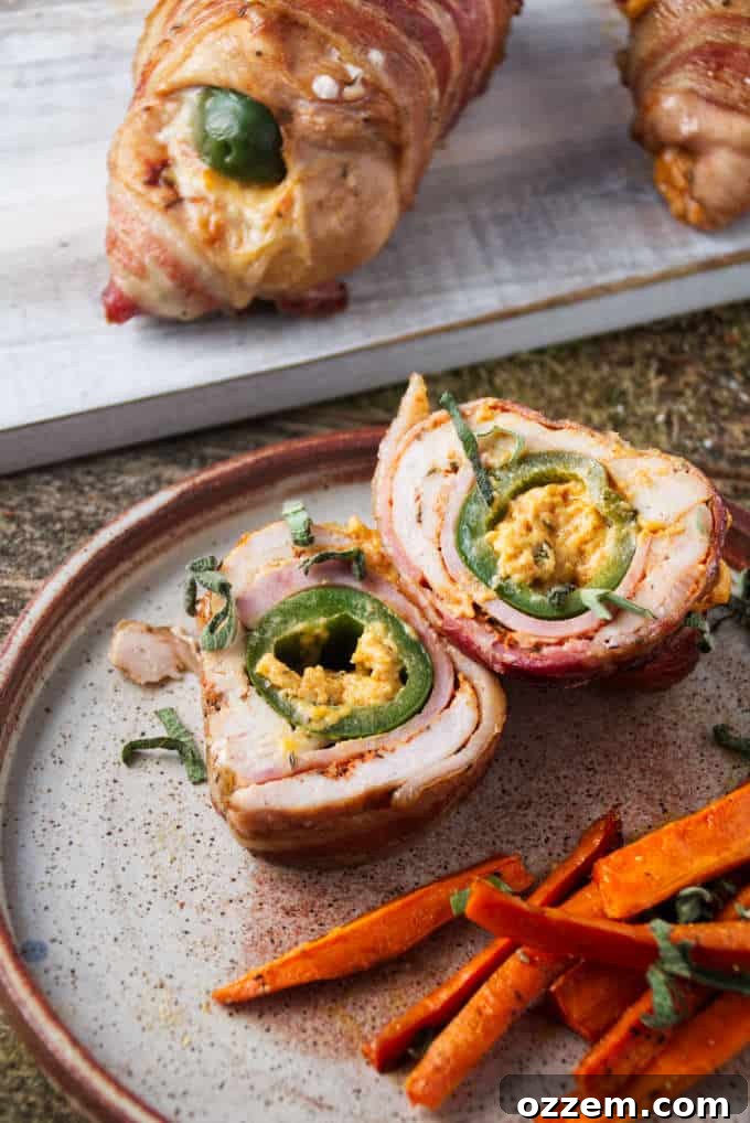 Smoked jalapeño popper stuffed chicken breast sliced and plated with some air fryer carrots with two unsliced pieces of chicken in background.