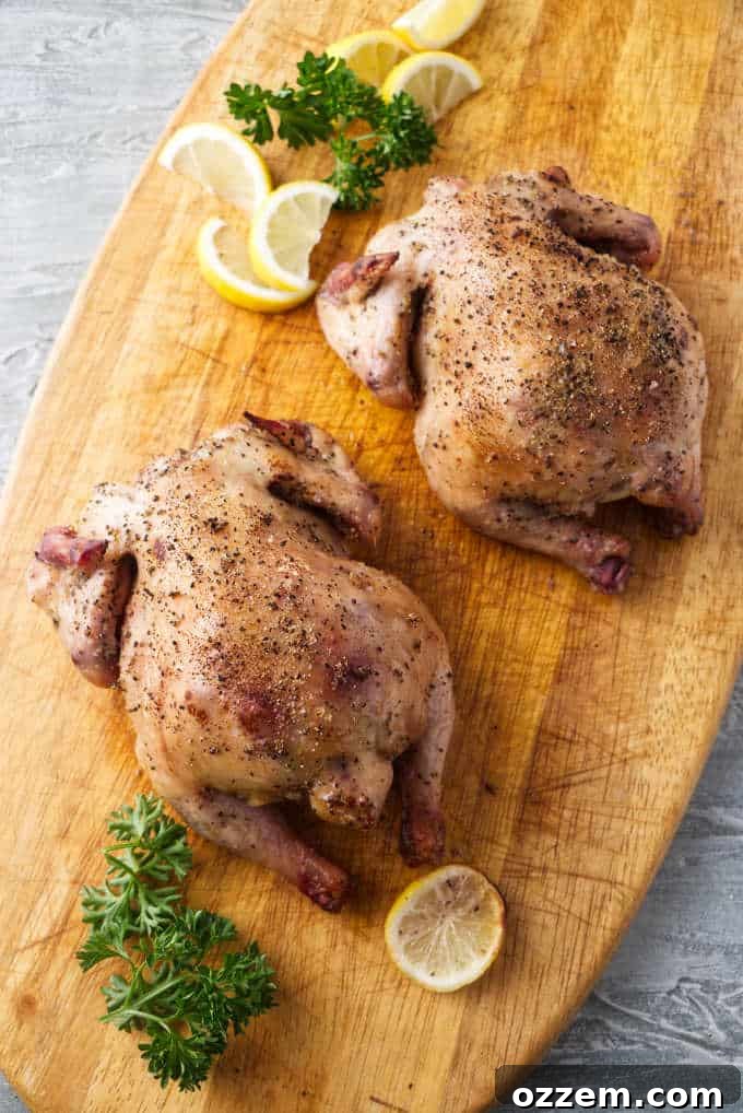 Perfectly Smoked Traeger Cornish Game Hens 3 Two perfectly smoked Cornish game hens resting on a wooden cutting board, ready to be carved.