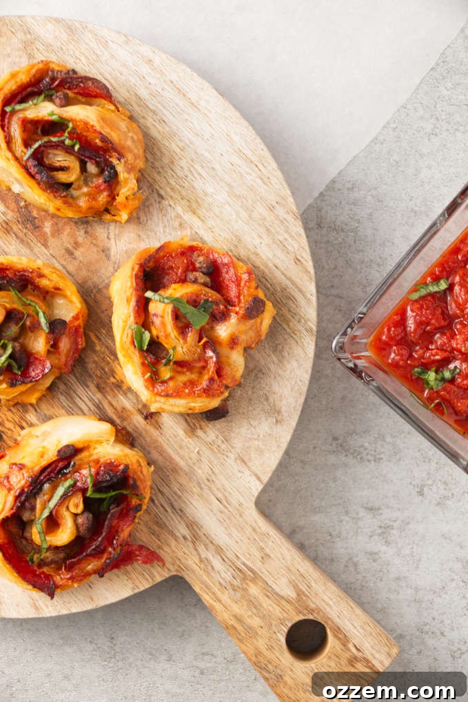 Crispy Homemade Air Fryer Pizza Rolls 2 Crispy air fryer pizza rolls on cutting board with pizza sauce in bowl for dipping.