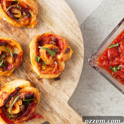 Crispy air fryer pizza rolls on cutting board with pizza sauce in bowl for dipping.