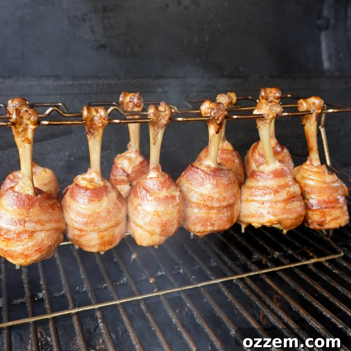 Crispy Bacon Chicken Legs 8 Grilled bacon wrapped chicken drumsticks on the smoker, close-up.