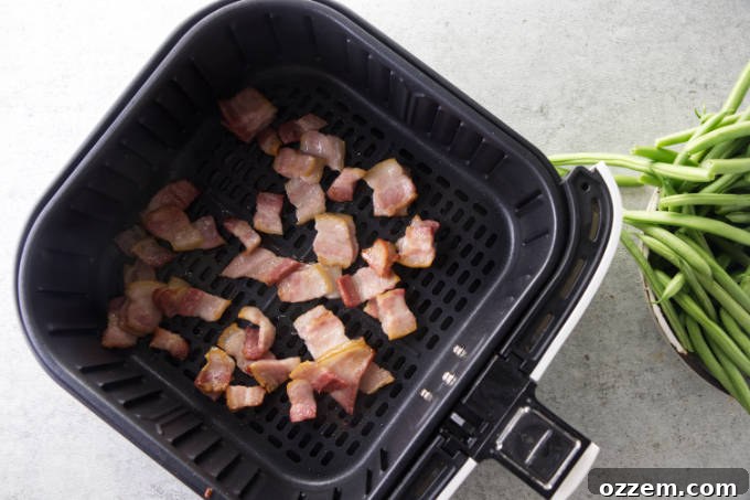 Bacon bits cooking in a hot air fryer basket, becoming crispy.