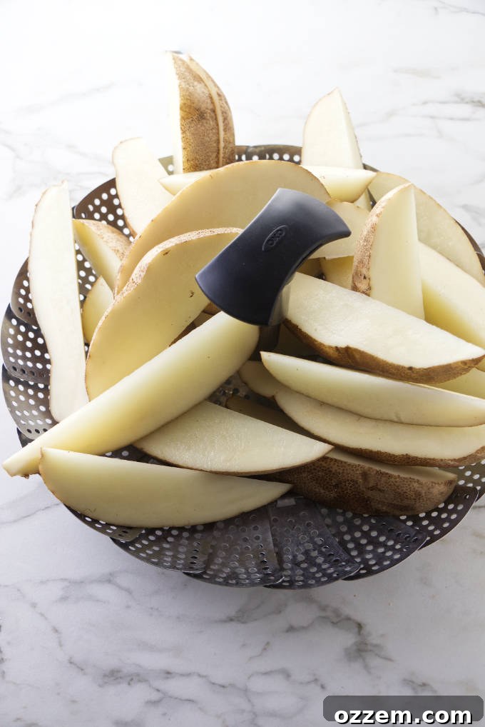 Several neatly sliced potato wedges being carefully placed into a metal steamer basket.