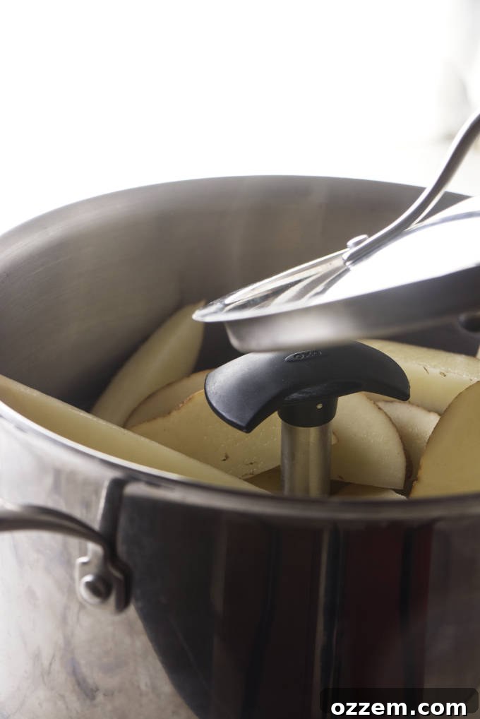 Potato wedges steaming inside a large metal pot covered with a lid on a stovetop burner.