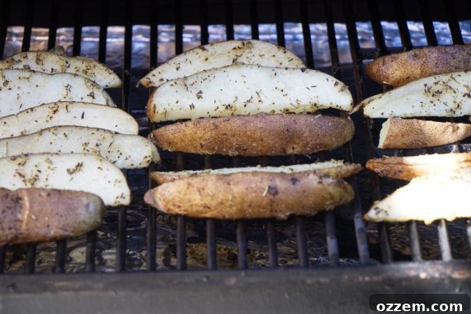 Close-up of seasoned potato wedges sizzling on hot grill grates, showing distinct grill marks beginning to form.