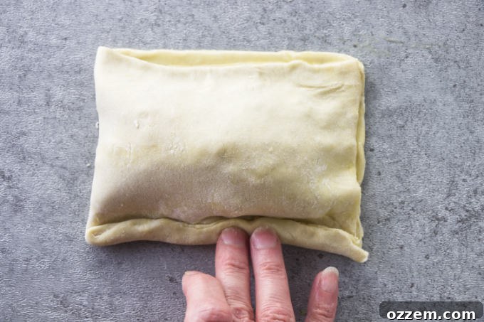 Carefully folding one half of the pastry over the filling to create a sealed breakfast pocket.