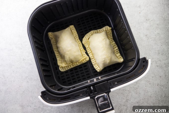 Uncooked breakfast pockets arranged neatly inside an air fryer basket, ready for cooking.