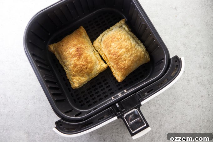 Golden brown, freshly baked air fryer breakfast pockets cooling on a wire rack after being cooked, showcasing their crispy texture.