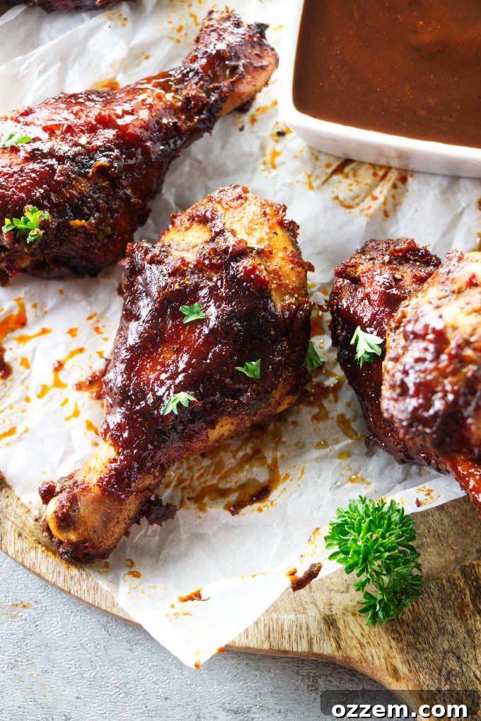 Air fryer drumsticks next to some bbq sauce.