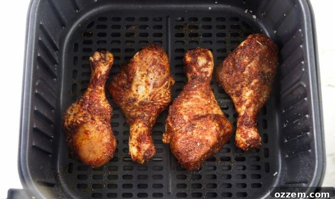Chicken legs coated in dry rub and placed in an air fryer basket.