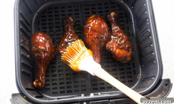 Coating chicken legs with bbq sauce.
