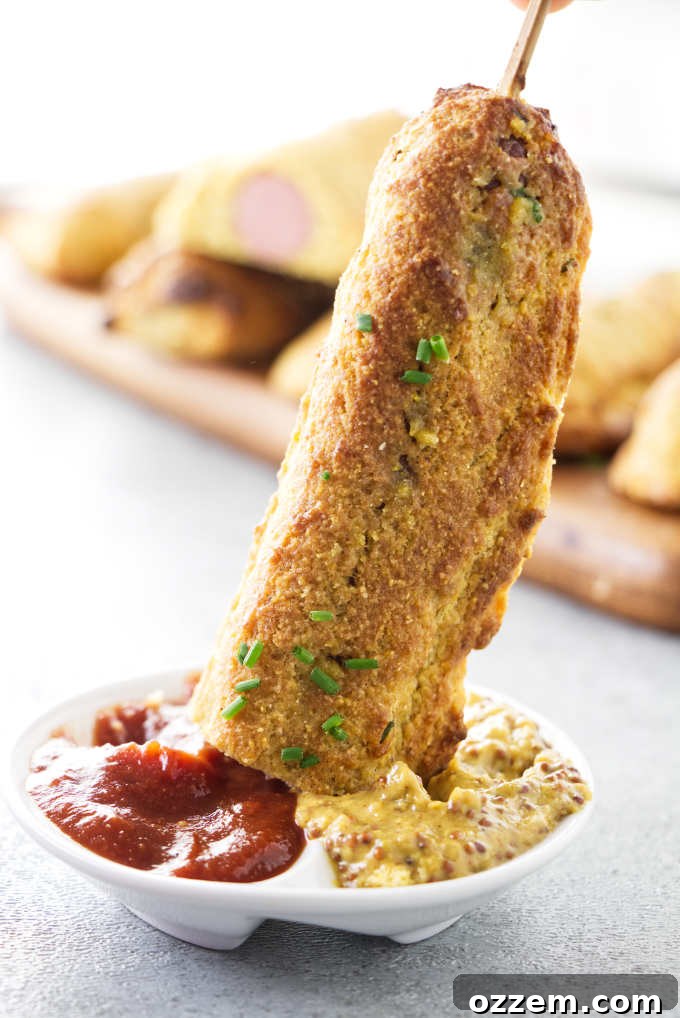 A corn dog being dipped into ketchup.