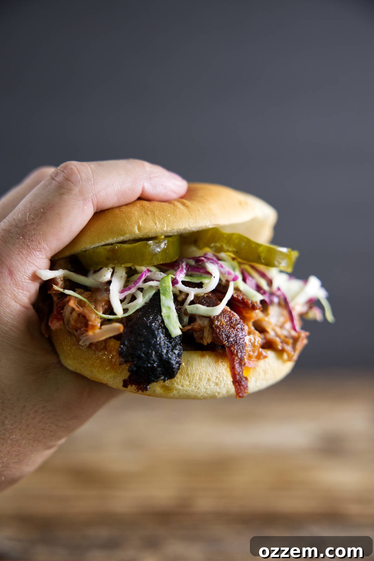 Pulled pork sandwich made from smoked pork butt (smoked pork shoulder). With pickles, slaw, and BBQ sauce.
