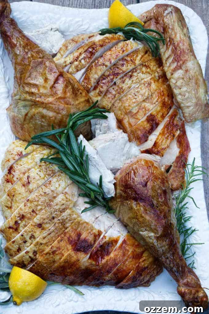 Sliced pellet grill smoked turkey on a serving tray with fresh herbs, ready to be enjoyed.